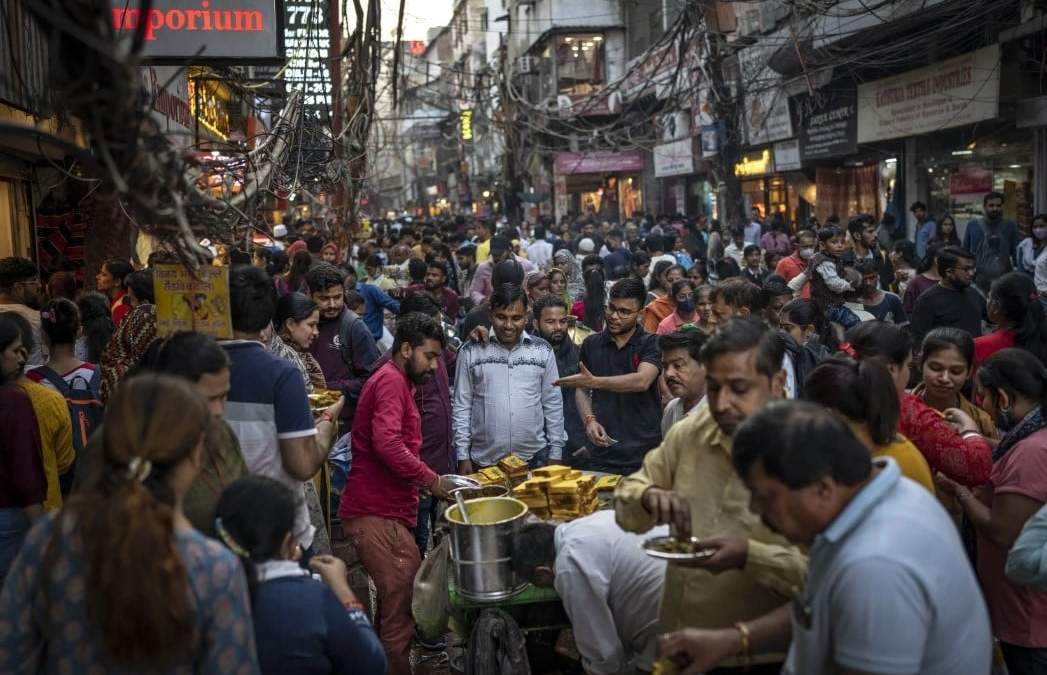 Gente toma comida callejera en un mercado abarrotado en Nueva Delhi, India