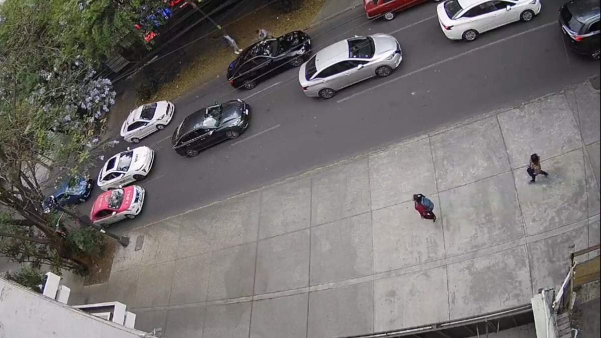 El momento en que un asaltante se acerca al auto negro