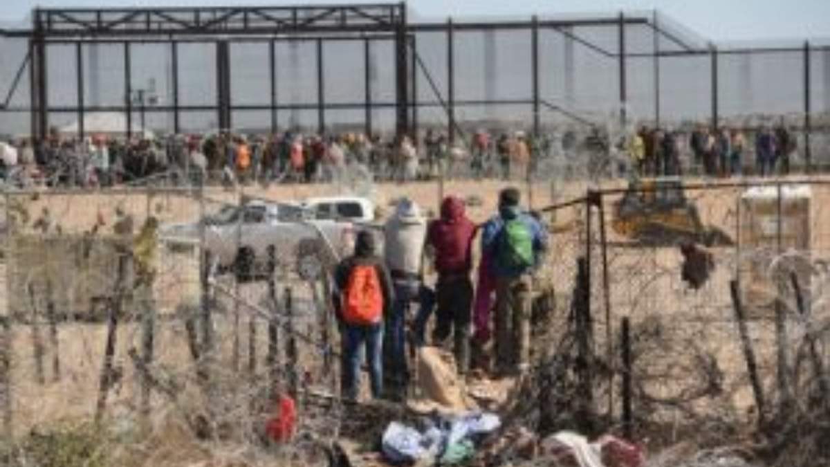 Migrantes cruzan y brincan la malla de alambre de púas en la puerta 36 de la frontera entre México y los Estados Unidos