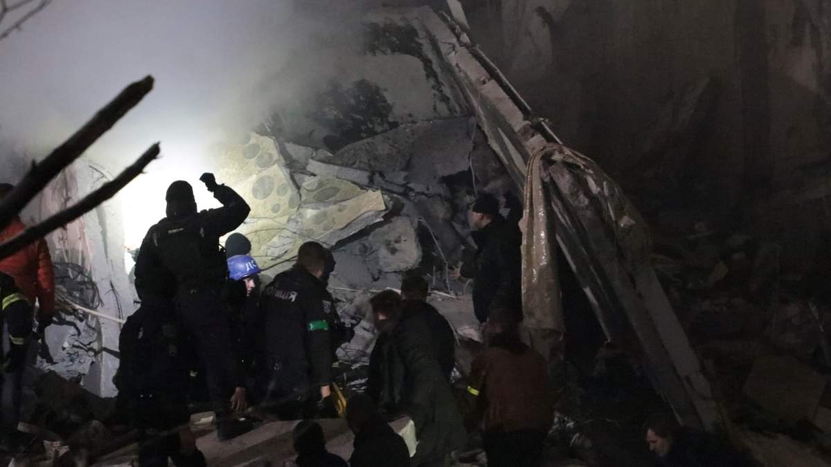 Trabajadores de emergencia limpian los escombros después de que un cohete ruso impactara en un edificio en Dnipro