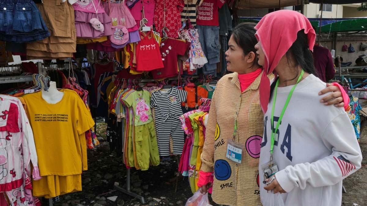 Trabajadoras textiles miran ropa a la venta durante un descanso para comer en una acera en el poblado de Ang Tako, a las afueras de Phnom Penh, Camboya