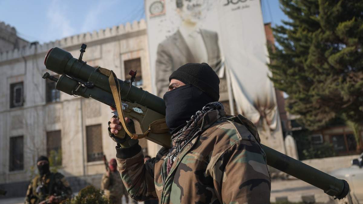 Un combatiente de la oposición siria sostiene un lanzacohetes ante una oficina gubernamental en Hama