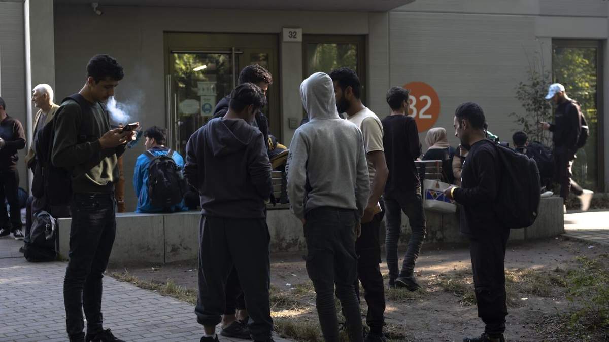 ARCHIVO - Docenas de migrantes provenientes de distintas partes del mundo se forman frente a un centro de registro para solicitantes de asilo, en Berlín, Alemania