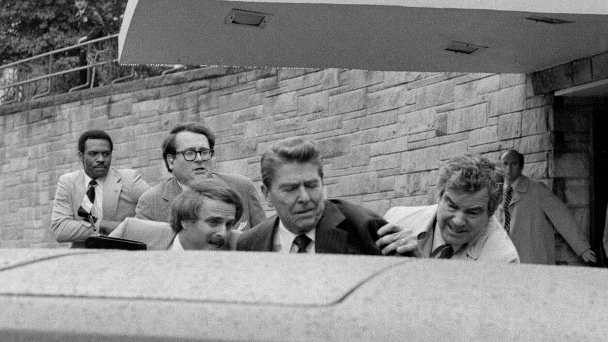 El presidente Ronald Reagan es empujado hacia su limusina por agentes del Servicio Secreto tras ser baleado el 30 de marzo de 1981