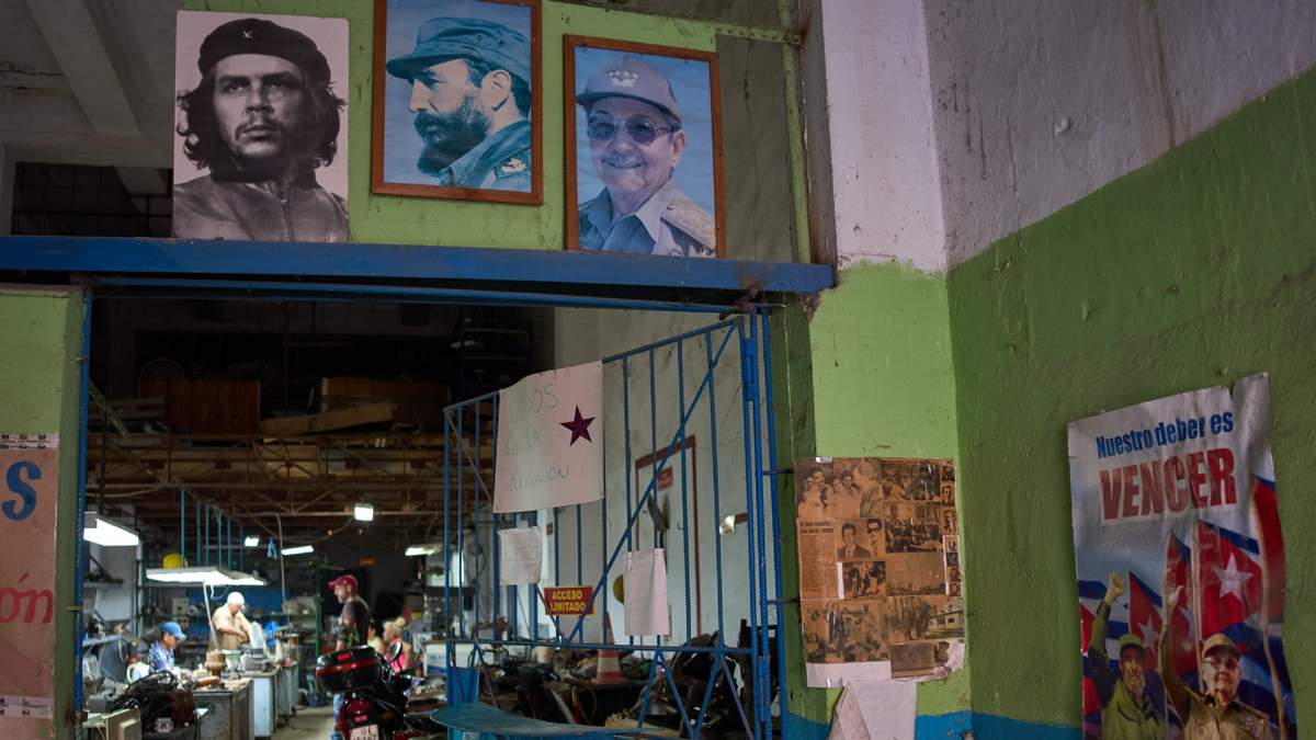 Carteles del héroe revolucionario cubano Ernesto "Che" Guevara, arriba a la izquierda, del fallecido líder cubano Fidel Castro, arriba en el centro, y de su hermano, el exlíder cubano Raúl Castro, cuelgan en la entrada de un taller de reparación en La Habana, Cuba