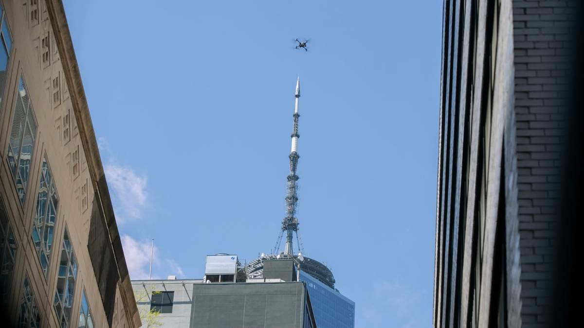 Un dron de la policía de Nueva York sobrevuela un estacionamiento parcialmente colapsado; al fondo se ve el One World Trade Center