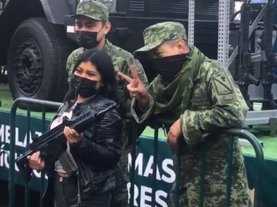 Asistentes al desfile posan con armas prestadas por militares y se desatan críticas en redes