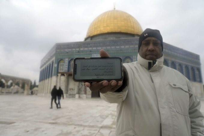 Un musulmán en la Mezquita de Al-Aqsa en la zona antigua de Jerusalén muestra en su celular un mensaje amenazante