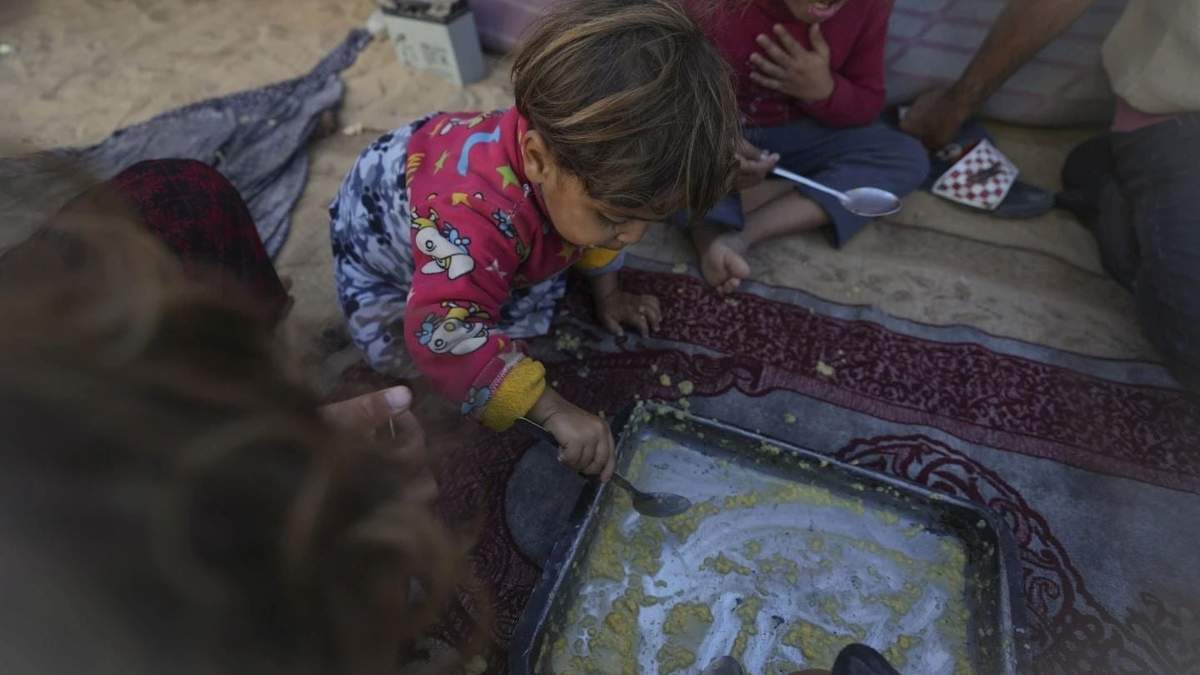 Las niñas de la familia Eid comen lentejas cocinadas por su madre, Yasmin, en su tienda de campaña en un campo de refugiados en Deir al-Balah, Franja de Gaza, el martes 19 de noviembre de 2024.