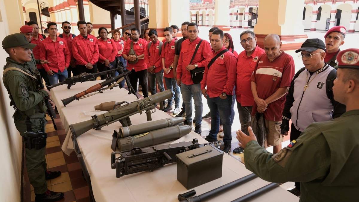 Un miembro de la guardia presidencial venezolana muestra armas a quienes se alistaron para unirse a las milicias civiles durante una campaña nacional de alistamiento convocada por el gobierno del presidente Nicolás Maduro, en el museo militar de Caracas