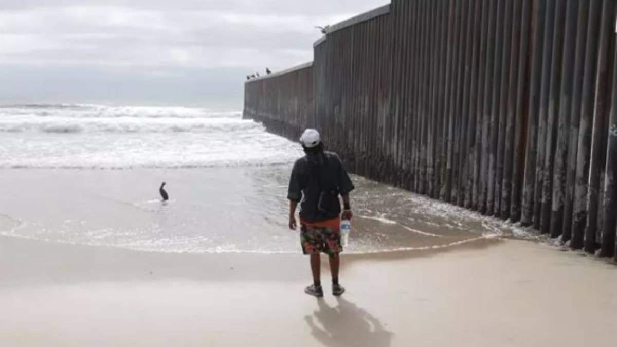Migrante en el muro de separación con EU