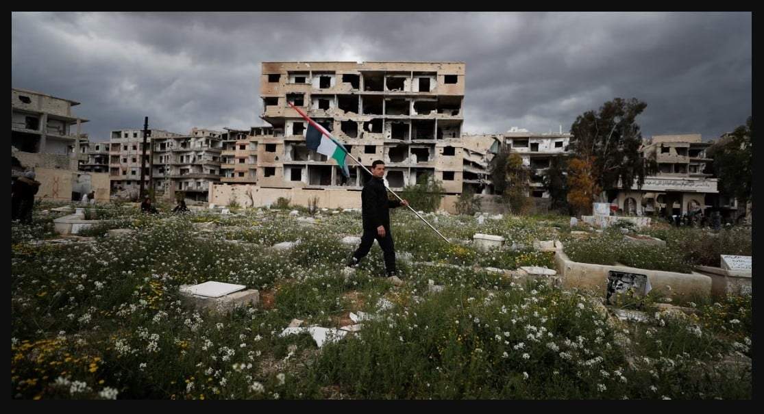 ARCHIVO - Un hombre lleva una bandera palestina en un campo de refugiados palestino en Yarmouk, en Damasco, Siria, el lunes 20 de marzo de 2023. Al menos siete personas fueron detenidas en Alemania y Suecia como sospechosas de cometer crímenes contra la humanidad y crímenes de guerra en Siria entre 2012 y 2014, según dijeron las autoridades de los dos países europeos