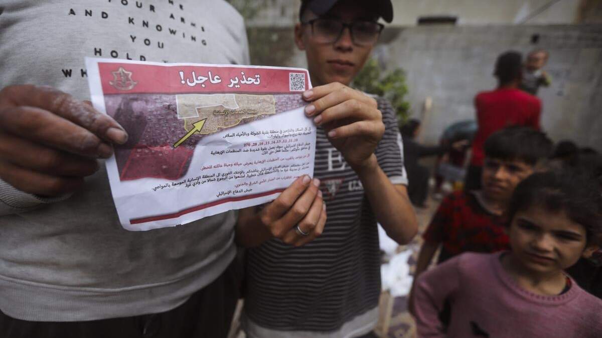 Palestinos sostienen folletos arrojados por aviones israelíes que les dicen que evacúen antes de una operación militar israelí en Rafah, en el sur de la Franja de Gaza, el lunes 6 de mayo de 2024. La orden afecta a decenas de miles de personas y podría apuntar a una invasión más amplia de la ciudad, que Israel ha identificado como el último bastión importante de Hamás tras siete meses de guerra
