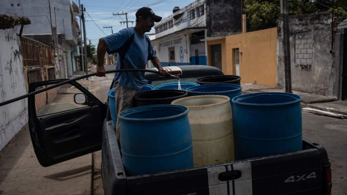 Un hombre llena contenedores con agua debido a la escasez causada por las altas temperaturas y la sequía en Veracruz, el 16 de junio de 2024