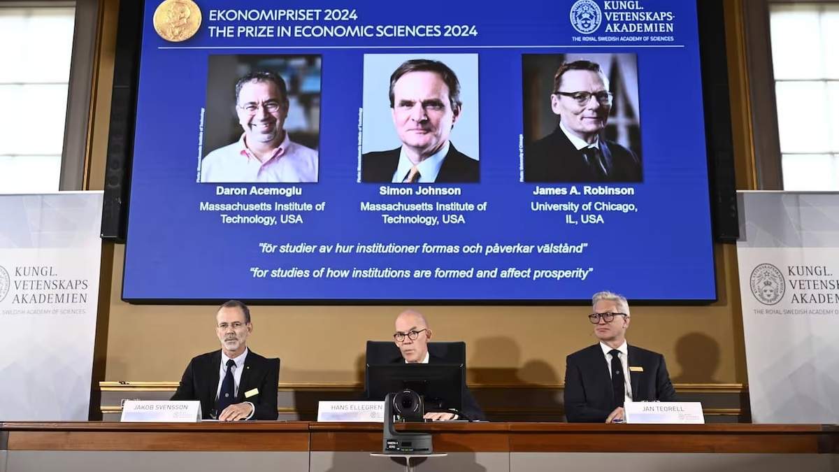 El secretario permanente de Ciencias, Hans Ellegren, en el centro, Jakob Svensson, a la izquierda, y Jan Teorell, de la asamblea del Nobel, anuncian el Premio del Banco de Suecia de Ciencias Económicas en Memoria de Alfred Nobel a Daron Acemoglu, Simon Johnson y James A Robinson, en la pantalla, durante una conferencia de prensa en la Academia Sueca de Ciencias en Estocolmo, Suecia