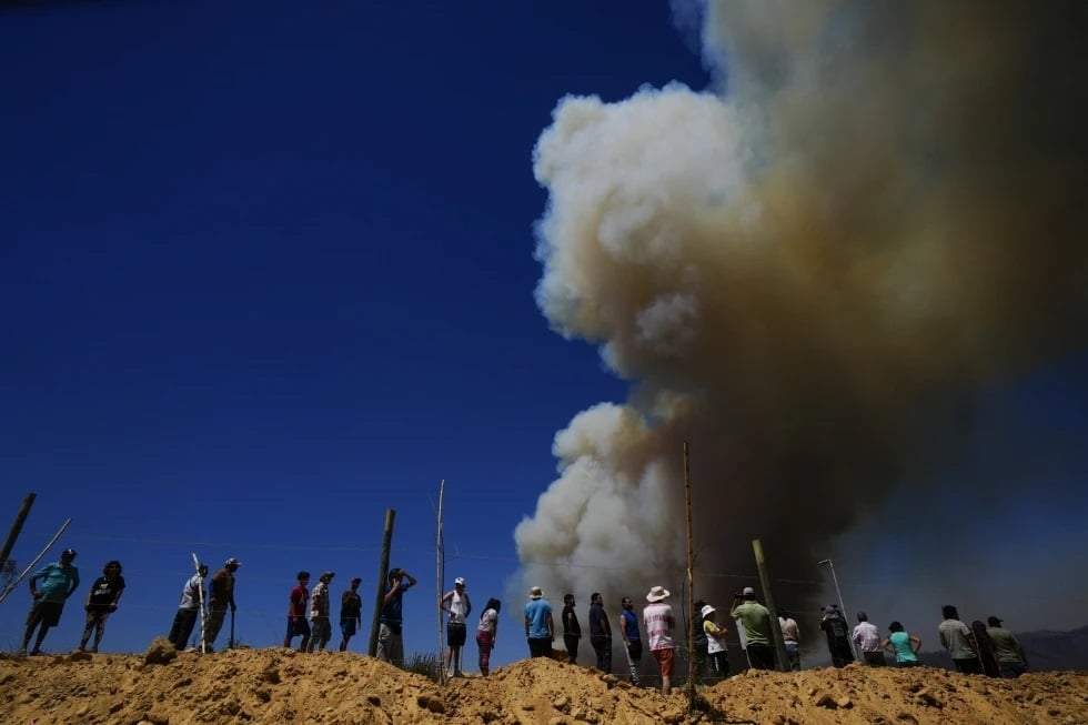 Residentes miran una columna de humo que asciende hacia el cielo, en Viña del Mar, Chile, el 3 de febrero de 2024