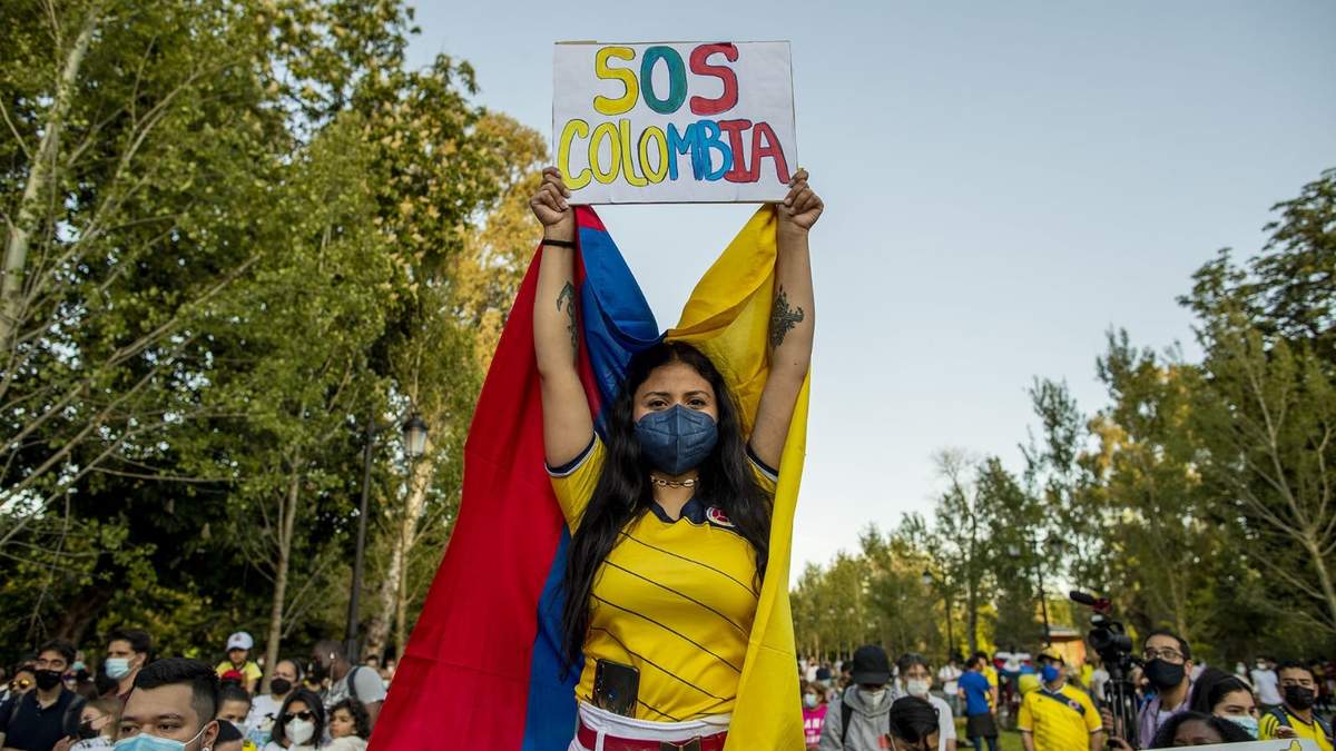 Una colombiana sostiene una pancarta de auxilio durante las protestas en Cali. Fuente: (Twitter)