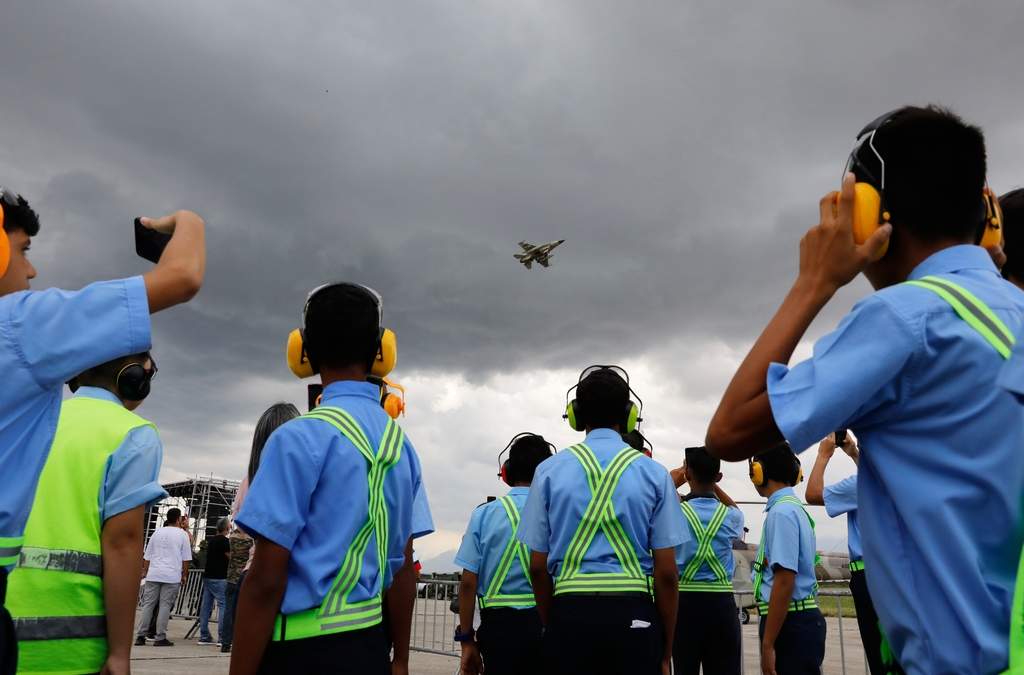 Estudiantes de mecánica aeronáutica observan el vuelo de exhibición de un avión de combate durante una exposición de aviación en la Base Aérea Libertador en Maracay, Venezuela, el sábado 29 de noviembre de 2025