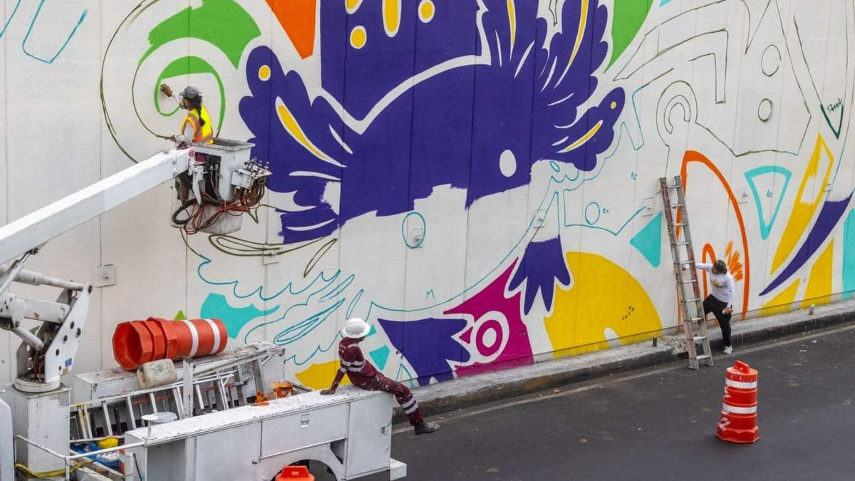 Trabajadores del gobierno capitalino realizan un mural alusivo al Mundial de Futbol; uno de los motivos principales es el ajolote y el color morado