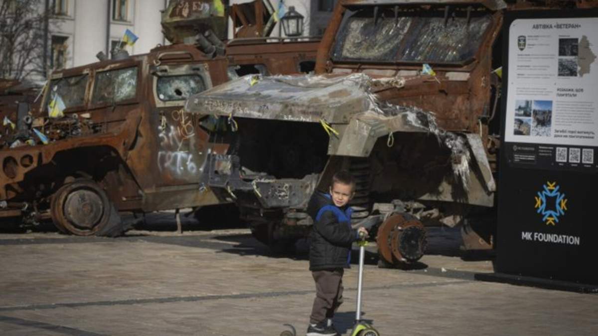 Un niño monta en patineta junto a una exposición de vehículos rusos destruidos en la plaza Mykhailivska del centro de Kiev, Ucrania