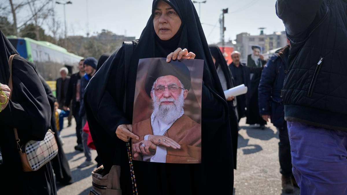 Una mujer muestra una fotografía del fallecido líder supremo de Irán, el ayatolá Ali Jamenei
