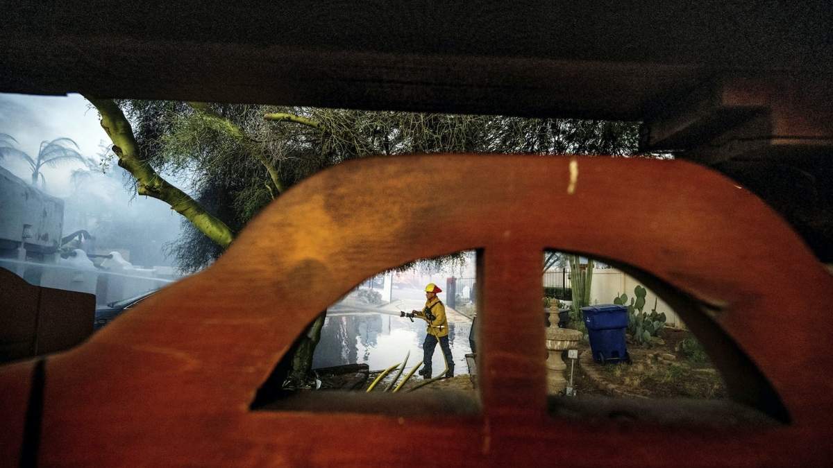 Un bombero limpia con una manguera el garaje de la casa de Noel Piri que fue destruida por el incendio de Hawarden en Riverside, California, el domingo 21 de julio