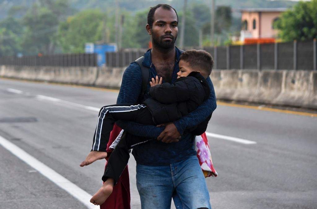 Un migrante carga a un niño en Tapachula