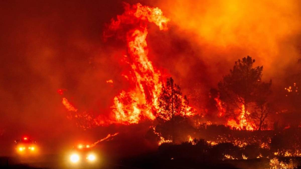 Las llamas saltan sobre los vehículos de bomberos mientras el incendio Park consume la autopista 36 cerca de Paynes Creek, en el condado de Tehama, California