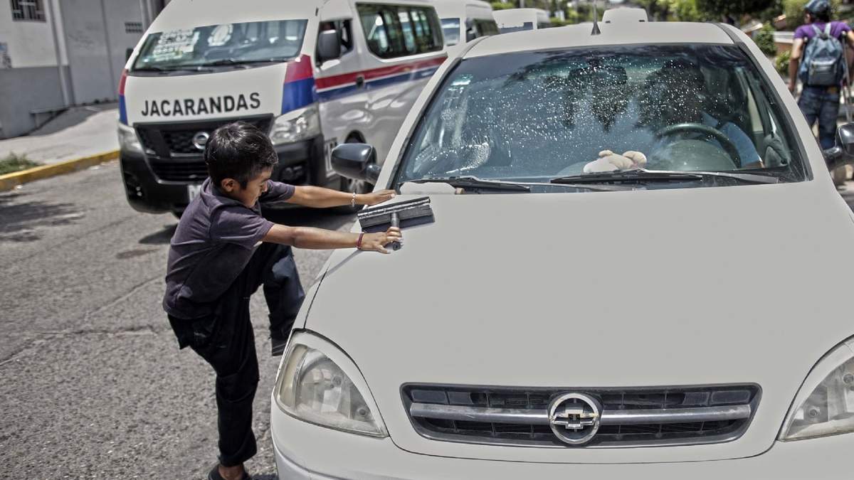 Un menor labora de limpiaparabrisas