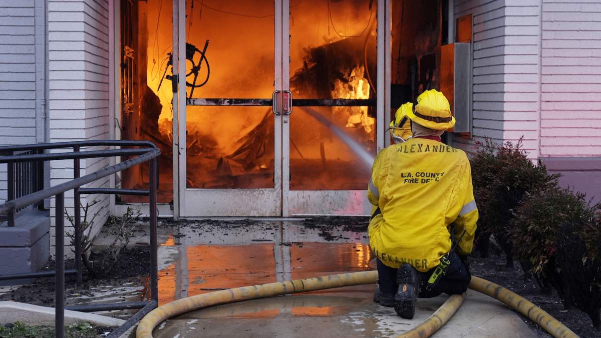 Bomberos combaten un incendio en la entrada de una sucursal de Bank of America envuelta en llamas en Lake Avenue