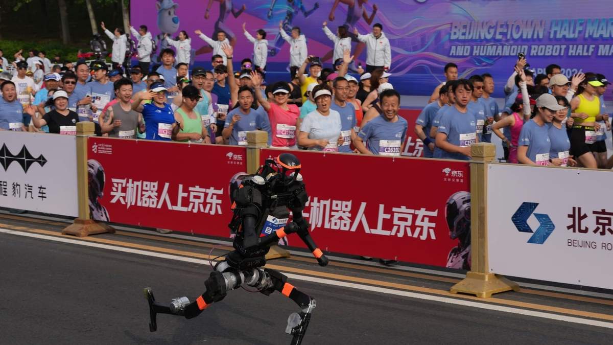 Un robot comienza a correr al lado de los corredores humanos para la II Media Maratón y Media Maratón de Robots Humaoides Beijing E-Town celebrada a las afueras de Beijing, el domingo 19 de abril de 2026