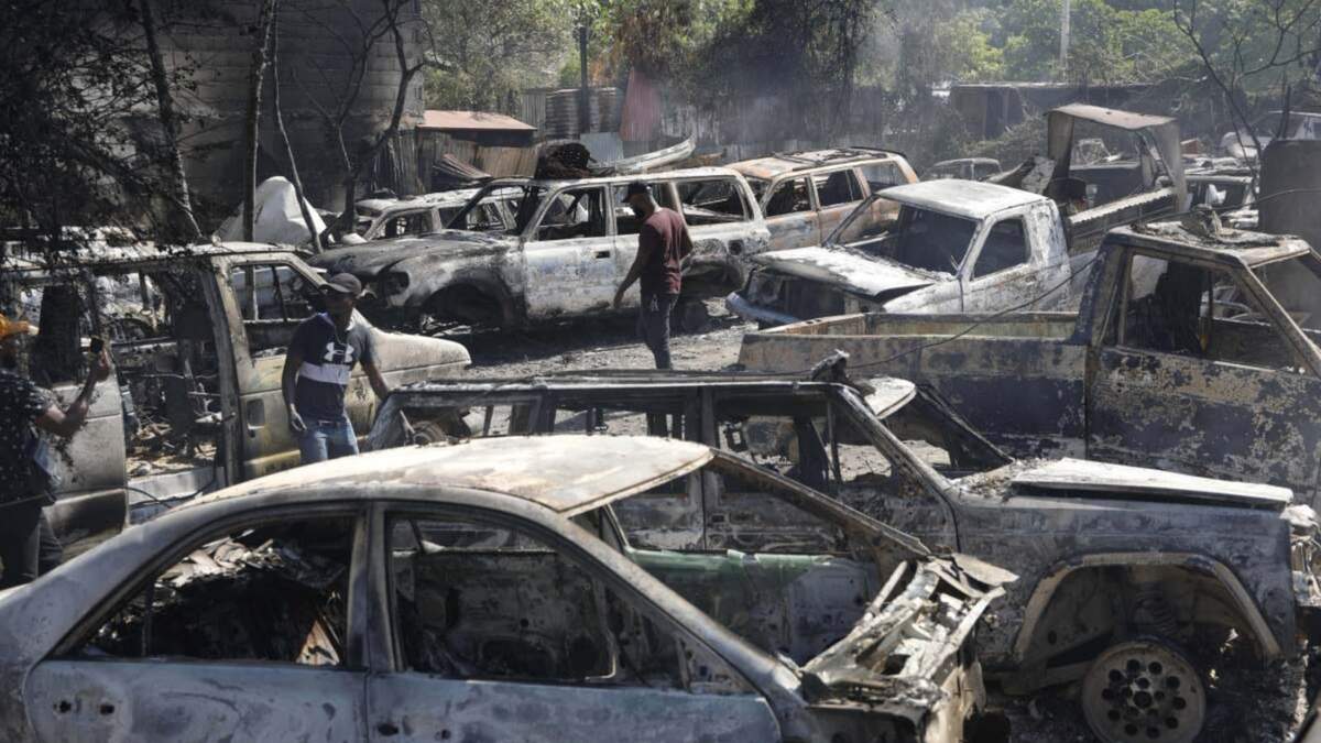 Varias personas buscan piezas rescatables de coches quemados en un taller mecánico incendiado durante la violencia desatada por pandillas armadas en Puerto Príncipe, Haití