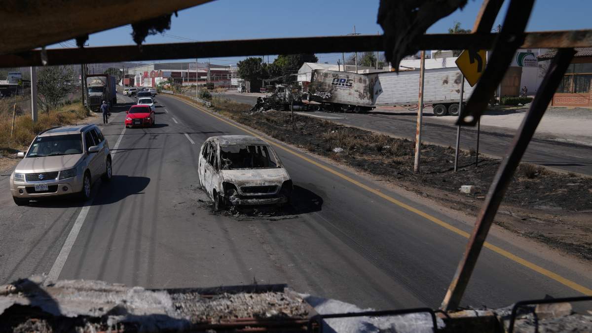 Vehículos pasan junto a un auto incendiado un día después de que el ejército mexicano matara al líder del Cártel Jalisco Nueva Generación