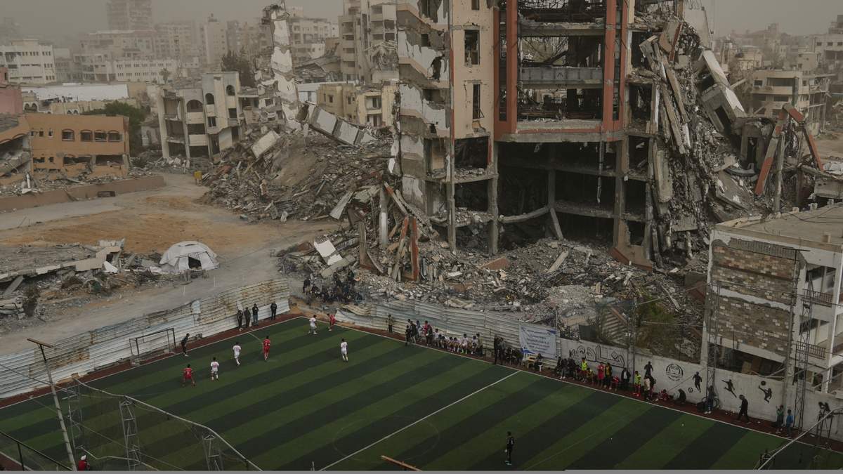 Jugadores palestinos del Club Deportivo Gaza y del Club Al-Ahly participan en un partido de fútbol en un campo de nueva construcción rodeado de edificios destruidos en Gaza