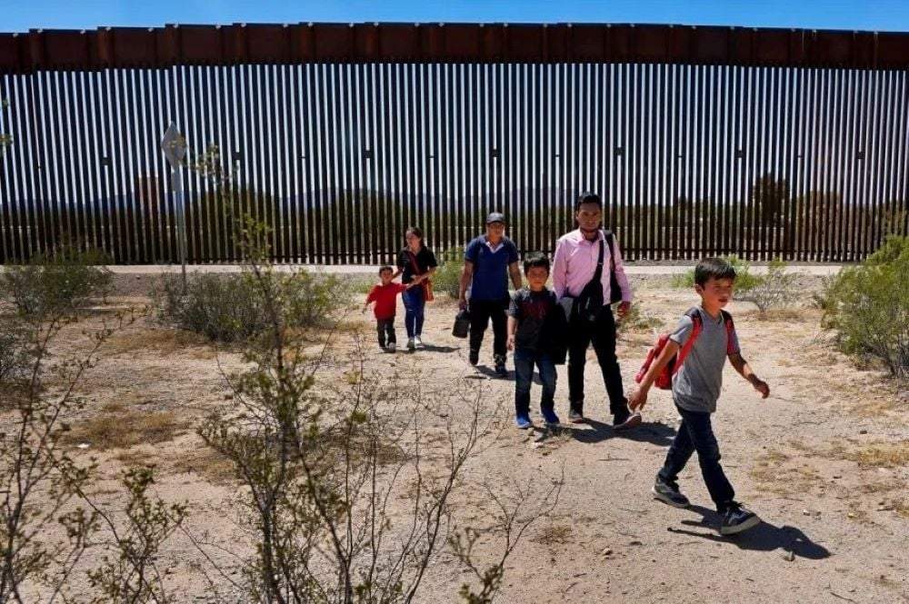 Una familia de cinco personas que dijo ser de Guatemala y un hombre que viaja con ellos que afirma es oriundo de Perú, de camisa rosa, caminan por el desierto tras cruzar el muro fronterizo en el Sector de Tucson de la frontera Estados Unidos-México, el martes 29 de agosto de 2023, en el Monumento Nacional Organ Pipe Cactus cerca de Lukeville, Arizona