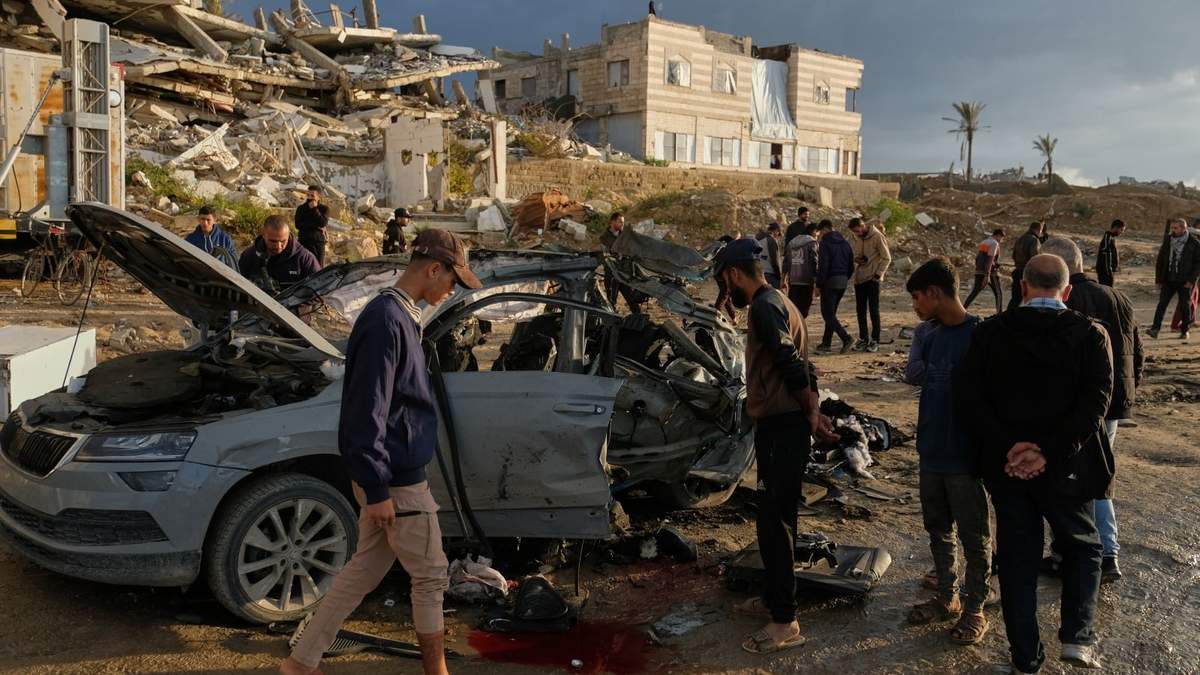 Varios palestinos observan un auto destruido tras un ataque israelí en la Ciudad de Gaza