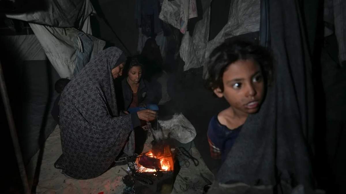 Shireen Daifallah, desplazada con sus hijos del norte de Gaza, comprueba el fuego junto a su tienda de campaña en un campamento de desplazados en Deir al-Balah, Franja de Gaza
