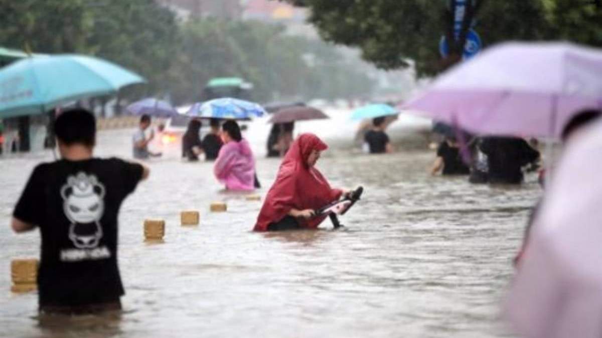 Gente camina por la carretera inundada después de lluvias récord en la ciudad de Zhengzhou, en Henan