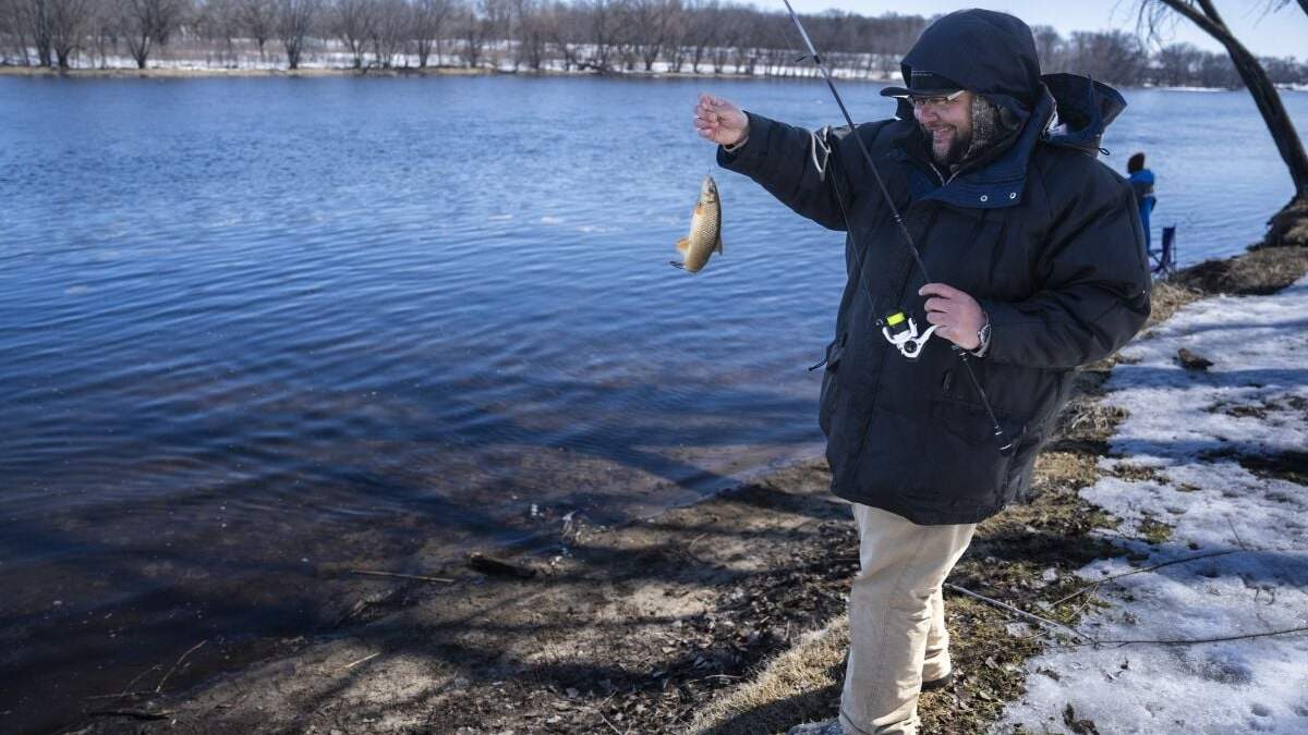Tyler Abayare pesca una carpa en el Mississippi río abajo de la planta nuclear Xcel Energy en Monticello, Minnesota