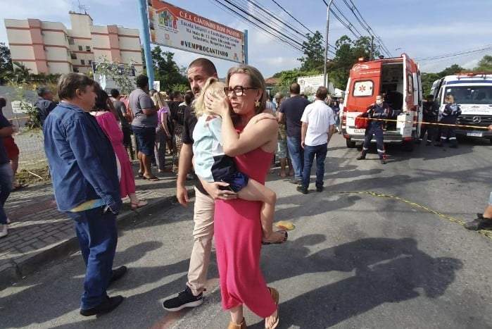 Una mujer reconforta a una niña que llora frente a la guardería Cantinho do Bom Pastor en Brasil