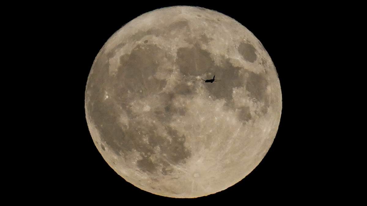 Un avión pasa frente a la Luna el 30 de agosto de 2023, en Chicago