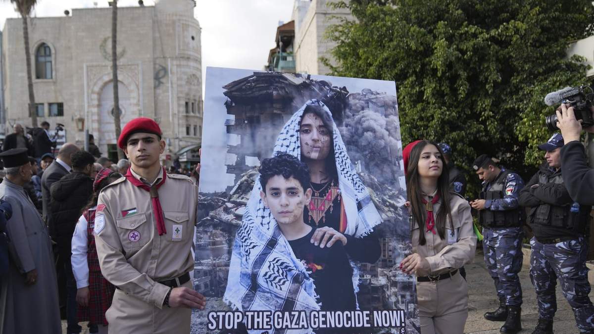 Scouts palestinos llevan un cartel mientras marchan durante las celebraciones de Nochebuena en la Iglesia de la Natividad el 24 de diciembre
