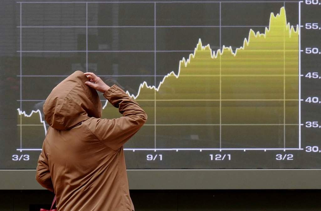 Una persona mira una pantalla con una gráfica del índice bursátil japonés Nikkei en una correduría en Tokio
