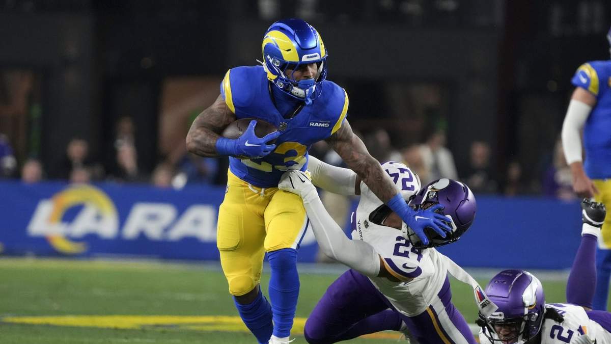 El corredor de los Rams de Los Ángeles Kyren Williams empuja al safety de los Vikings de Minnesota Camryn Bynum