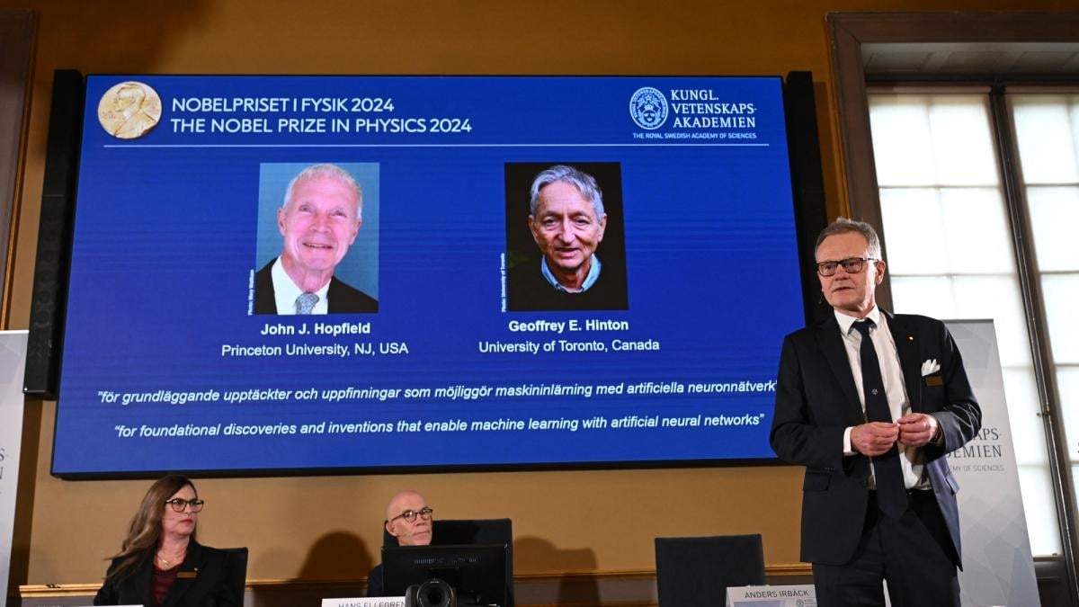John Hopfield y Geoffrey Hinton, aparecen en la pantalla en una conferencia de prensa en la que se anuncia que han ganado el Nobel de Física. En el centro aparece Hans Ellergren, secretario permanente de la Academia Sueca de Ciencias en Estocolmo