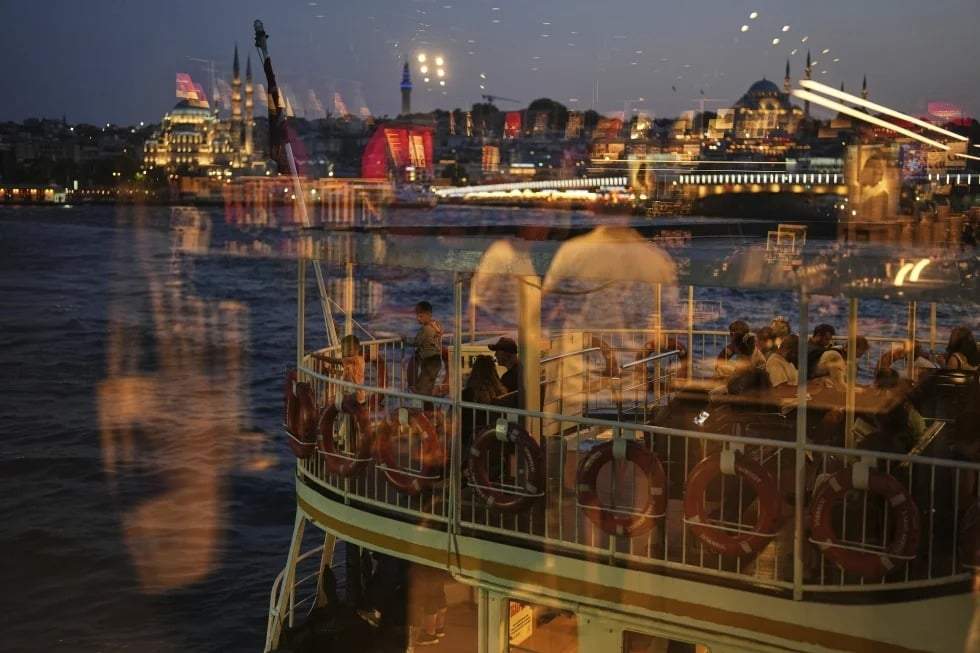 Pasajeros, vistos a través de una ventana, suben a bordo de un ferry antes de partir de la terminal de Karakoy, en Estambul, Turquía, el viernes 13 de junio de 2025.