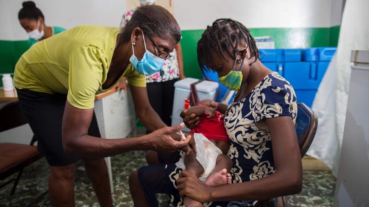 Un trabajador de la salud vacuna a Michaelle Laguerre, de 2 años, en una clínica de desnutrición