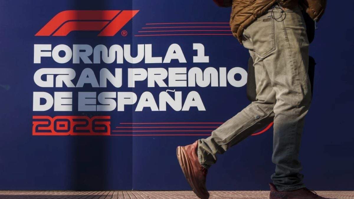 Un individuo camina frente al logo del Gran Premio de España en el palacio de convenciones IFEMA en Madrid, España