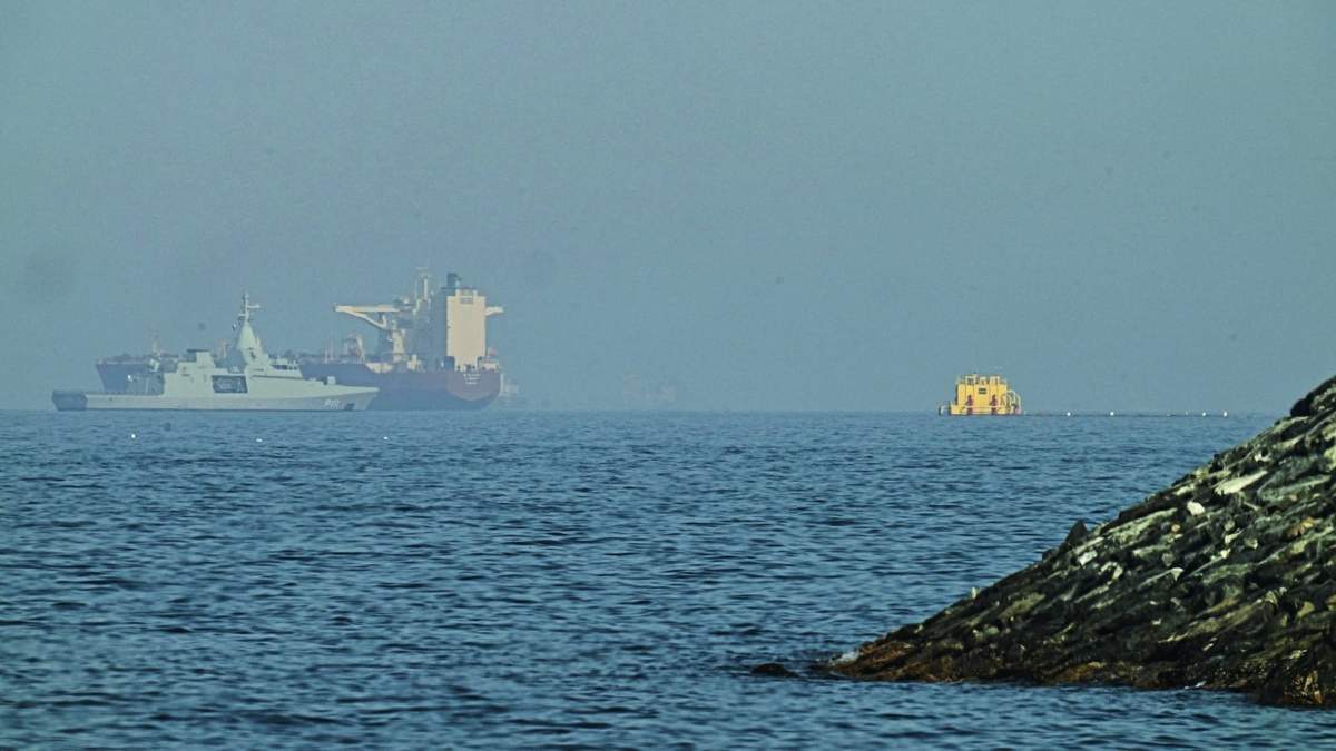 Una patrullera emiratí (izquieda), navega cerca de un petrolero fondeado en el golfo de Omán, cerca del estrecho de Ormuz