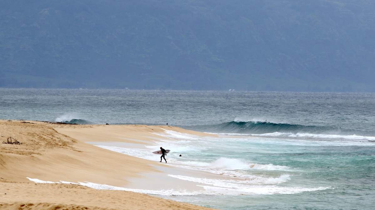 Un surfista sale del agua en la costa norte de Oahu